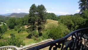 A scenic view from a balcony with a wrought iron railing, overlooking a lush landscape with trees and distant hills. - L'annexe du Château de Saint Genix (Saint-Genix-les-Villages)