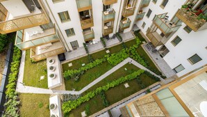 Un edifici residencial de diversos pisos amb balcons, zones d'estar a l'exterior i un pati central amb vegetació.