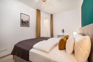 A neatly made bed with a brown blanket, white pillows, and a single brown pillow. - Vagabond Grand'Or (Budapest)