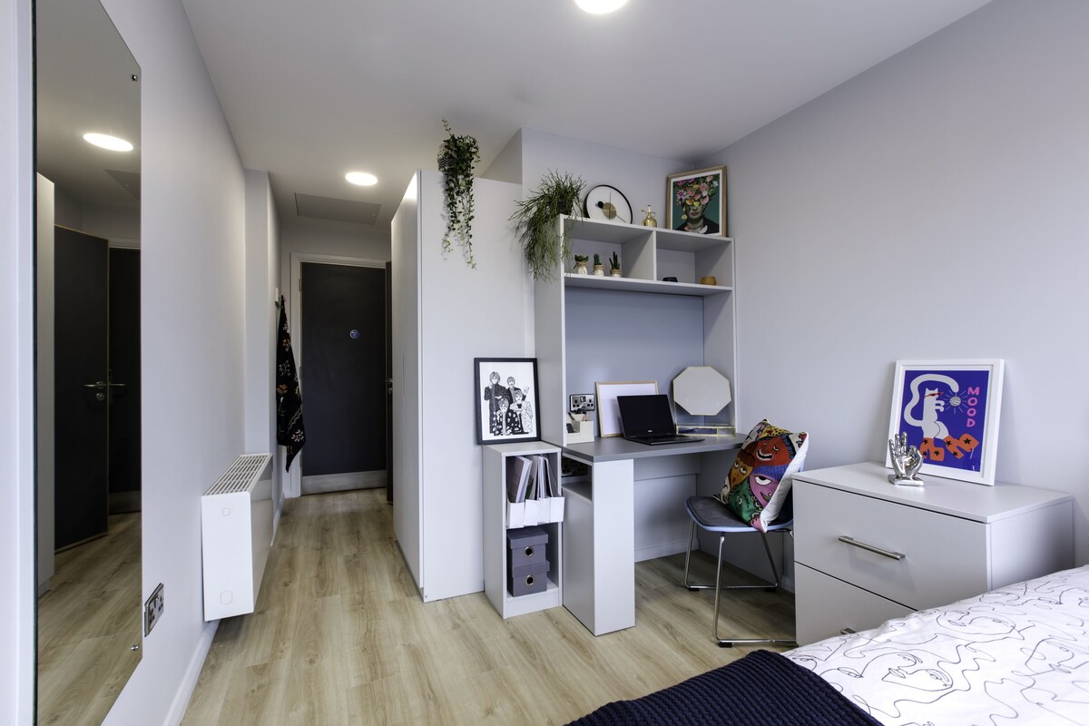 A modern bedroom with a desk, chair, and bed.