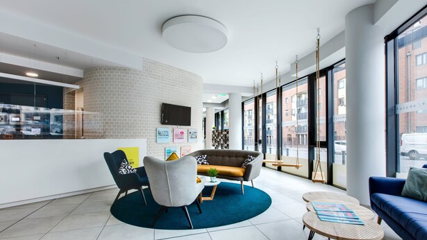 A modern lobby with a blue sofa, a grey armchair, and a round coffee table.