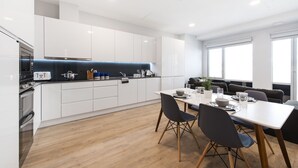 A modern kitchen with white cabinetry, a central island, and a dining area with a table and chairs.