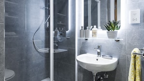 A modern bathroom with a glass-enclosed shower, a white sink, and a mirror above it.