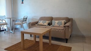 A living room with a sofa, a coffee table, a chair, and a small table.