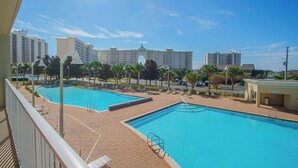 Zona de piscina con dos piscinas, una zona de estar techada y vistas a rascacielos al fondo.