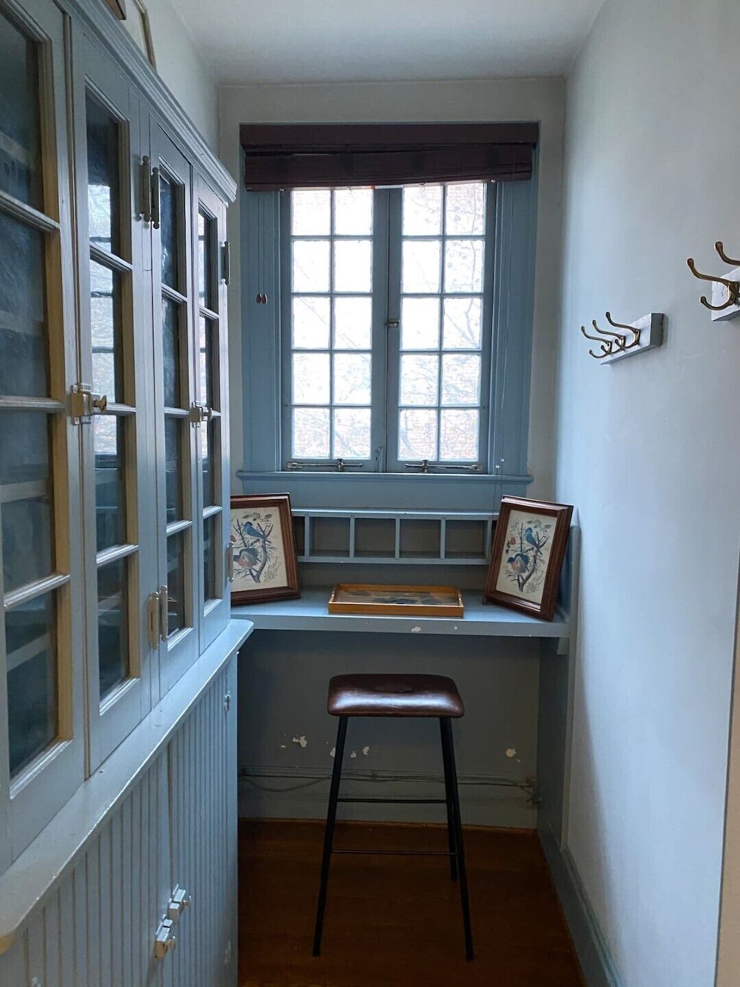 A narrow room with a window, a radiator, and a stool.