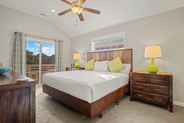 A bedroom with a large bed, wooden headboard, two bedside tables with lamps, a dresser, and a ceiling fan.
