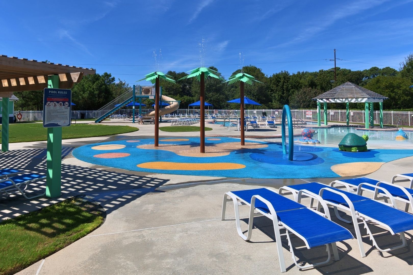 A water play area with slides and a pool, surrounded by lounge chairs and a covered seating area.