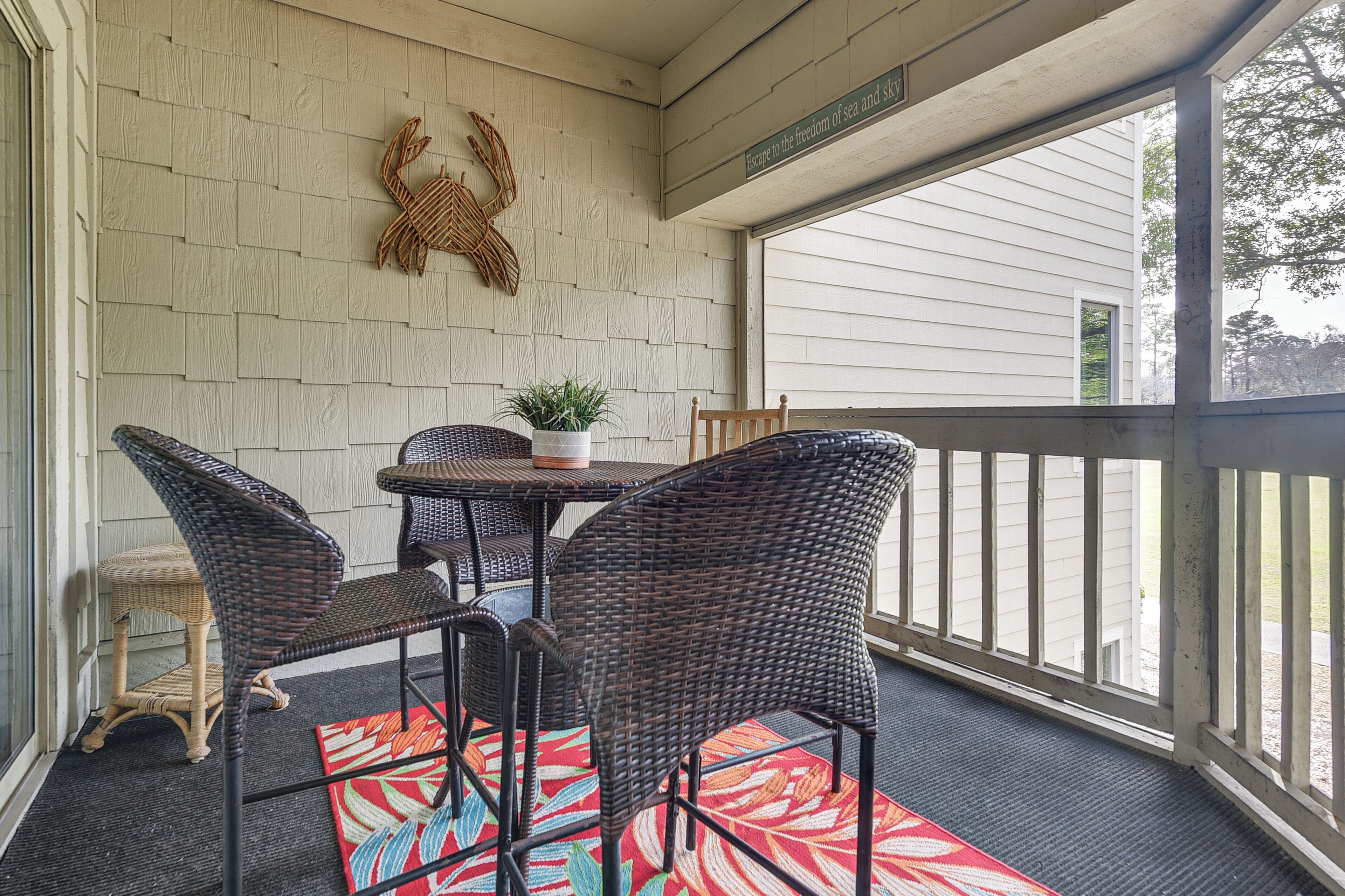 A covered patio with wicker furniture, a potted plant, and a decorative crab wall hanging.