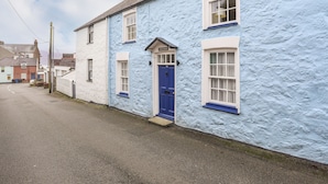 A narrow street with a blue house featuring a blue door and white-framed windows. - Bwthyn Dwyfor (Beaumaris)