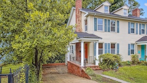 A two-story house with a front porch, a brick chimney, and a small front yard. - The Woodside Guest House II (Fayetteville)