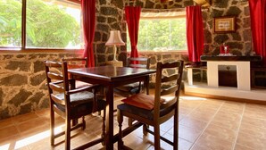 A rustic dining area with a stone wall, wooden table, and chairs. - Casa Tabobo - 2 bedroom rural house with breathtaking sea views and a hot tub. (Tías)