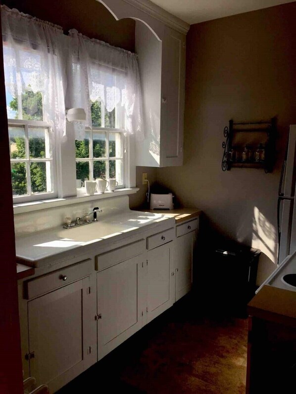 A kitchen with a window, white cabinets, a sink, and a countertop.