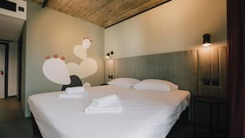 A hotel room with a large bed, a wooden ceiling, and a wall with a circular design.