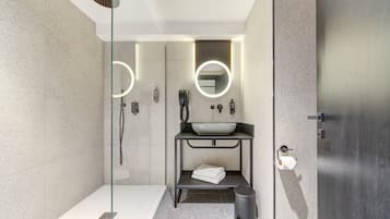 A modern bathroom with a glass-enclosed shower, a white sink, and a towel rack.