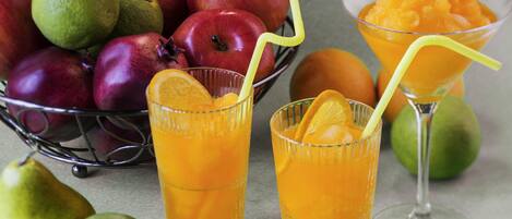 A fruit arrangement with apples, oranges, and a glass of orange juice.
