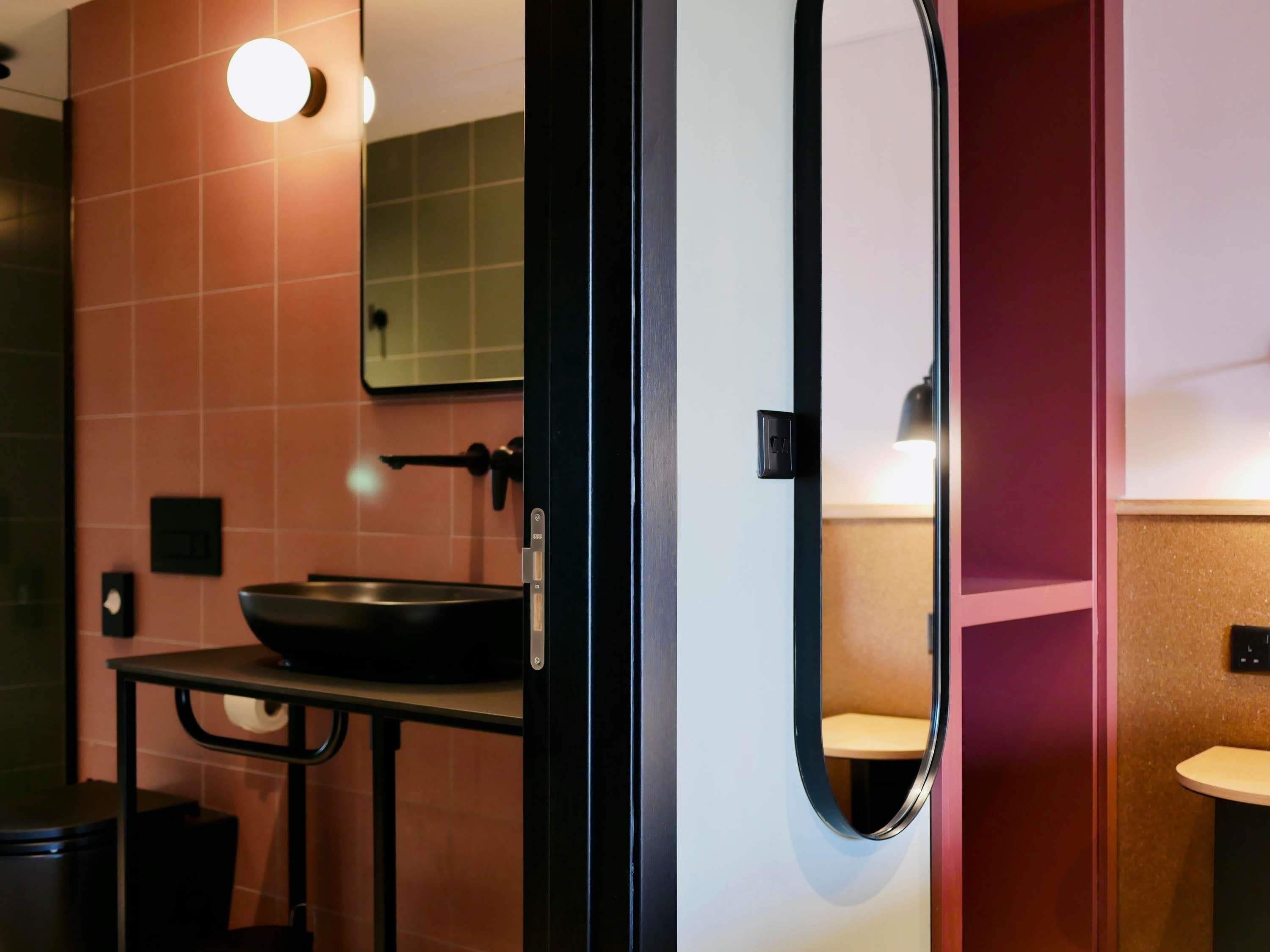 A bathroom with a round mirror, a sink, and a toilet.