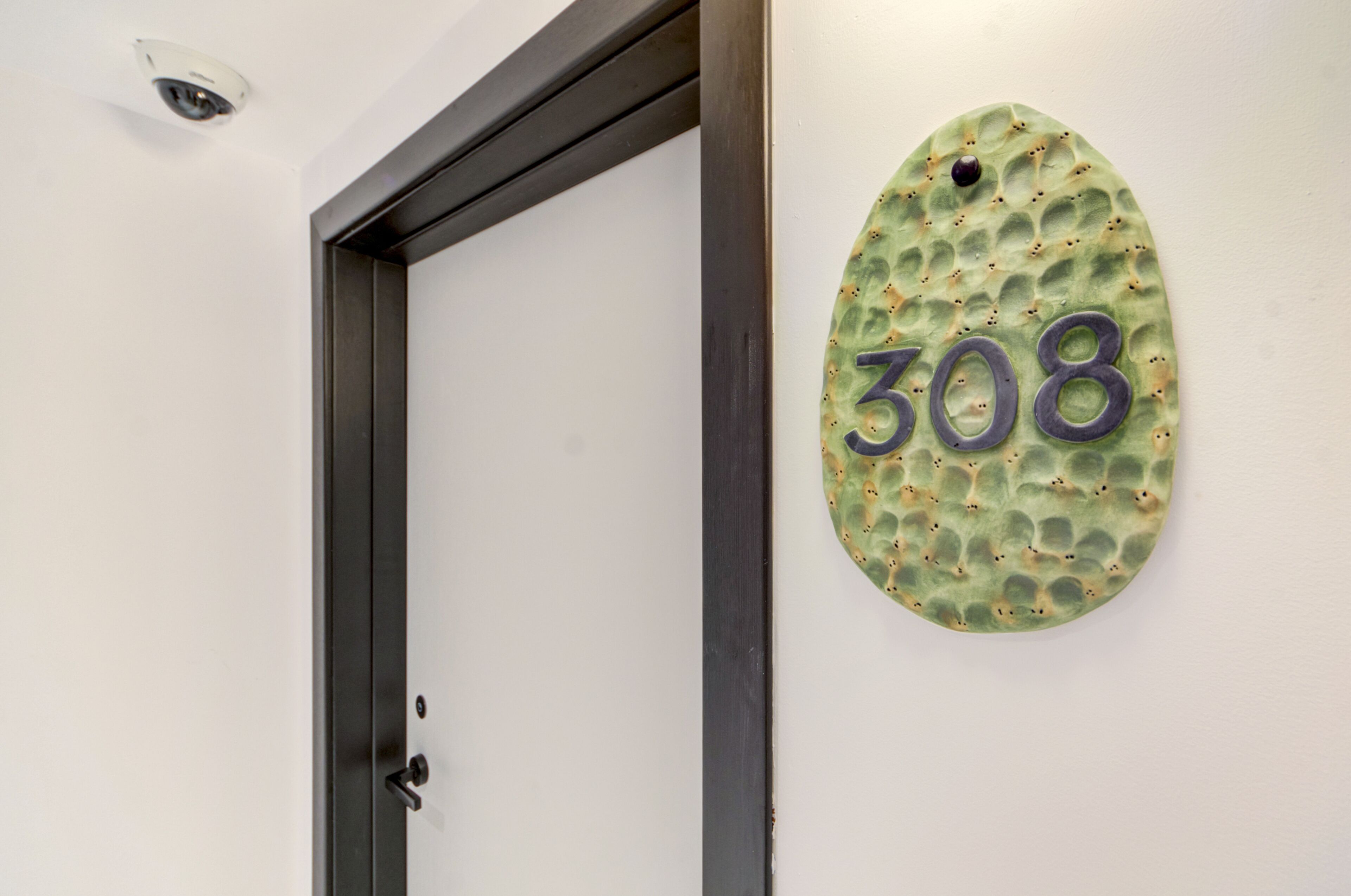 Une porte avec une plaque portant le numéro « 308 », fixée sur un mur à texture.