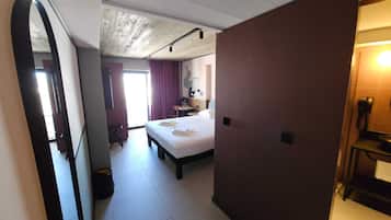 Ett hotellrum med en säng, ett skrivbord, en stol, ett litet bord och en toalett.
