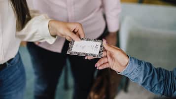 A person holding a business card with text and a logo.
