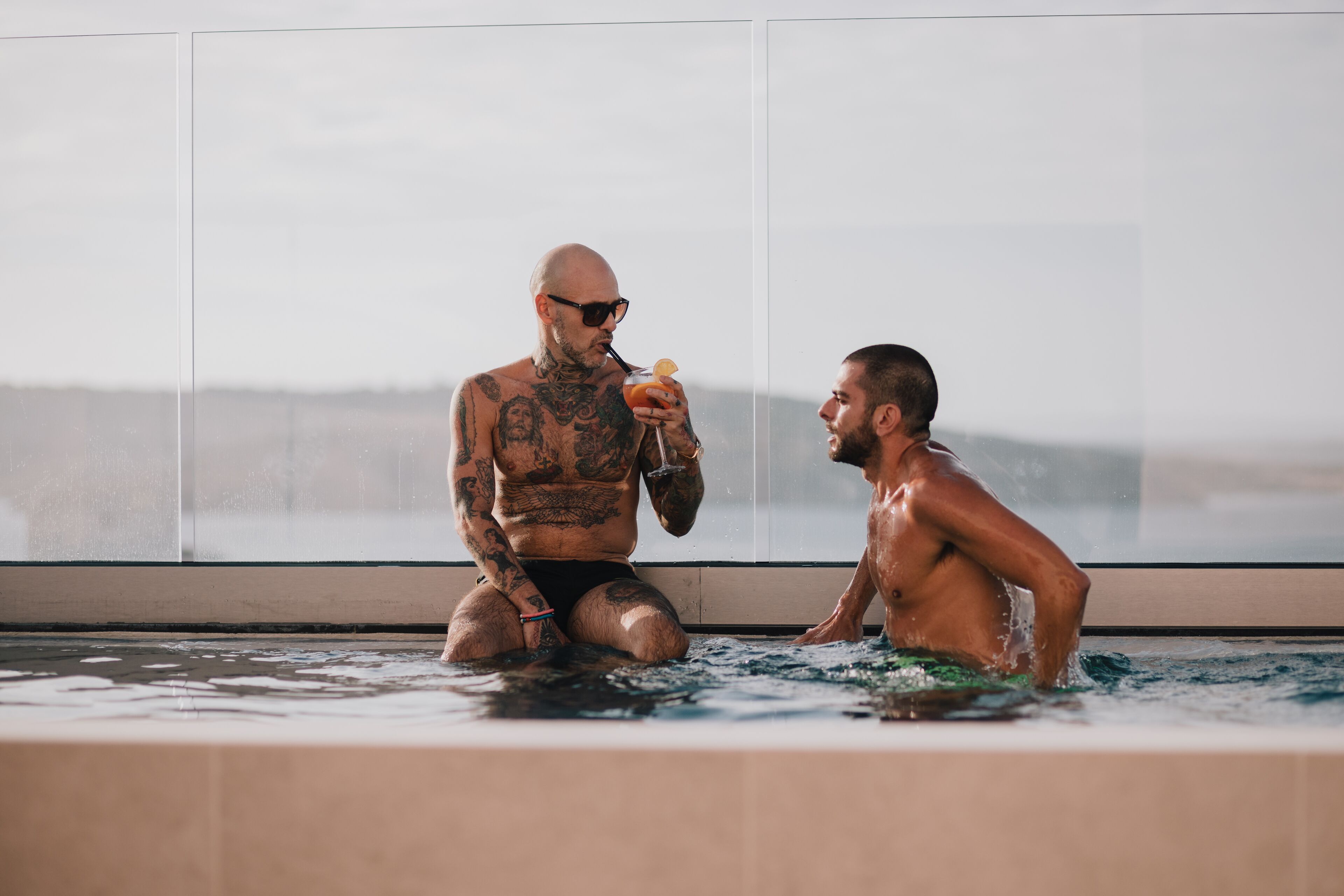 Two men in a hot tub with a view of the city skyline.