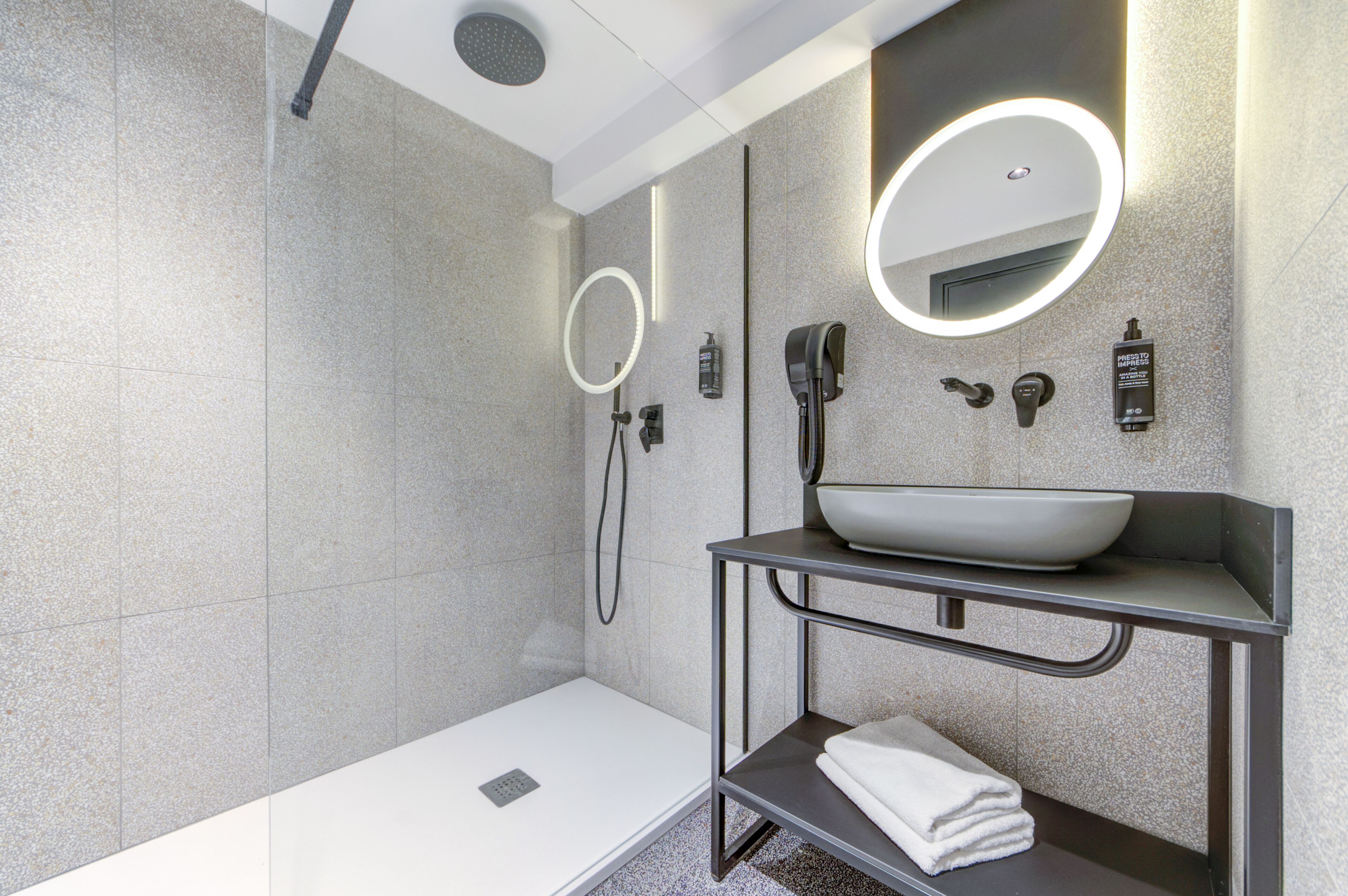 A modern bathroom with a white bathtub, a large mirror, a sink with a bowl, and a towel rack.