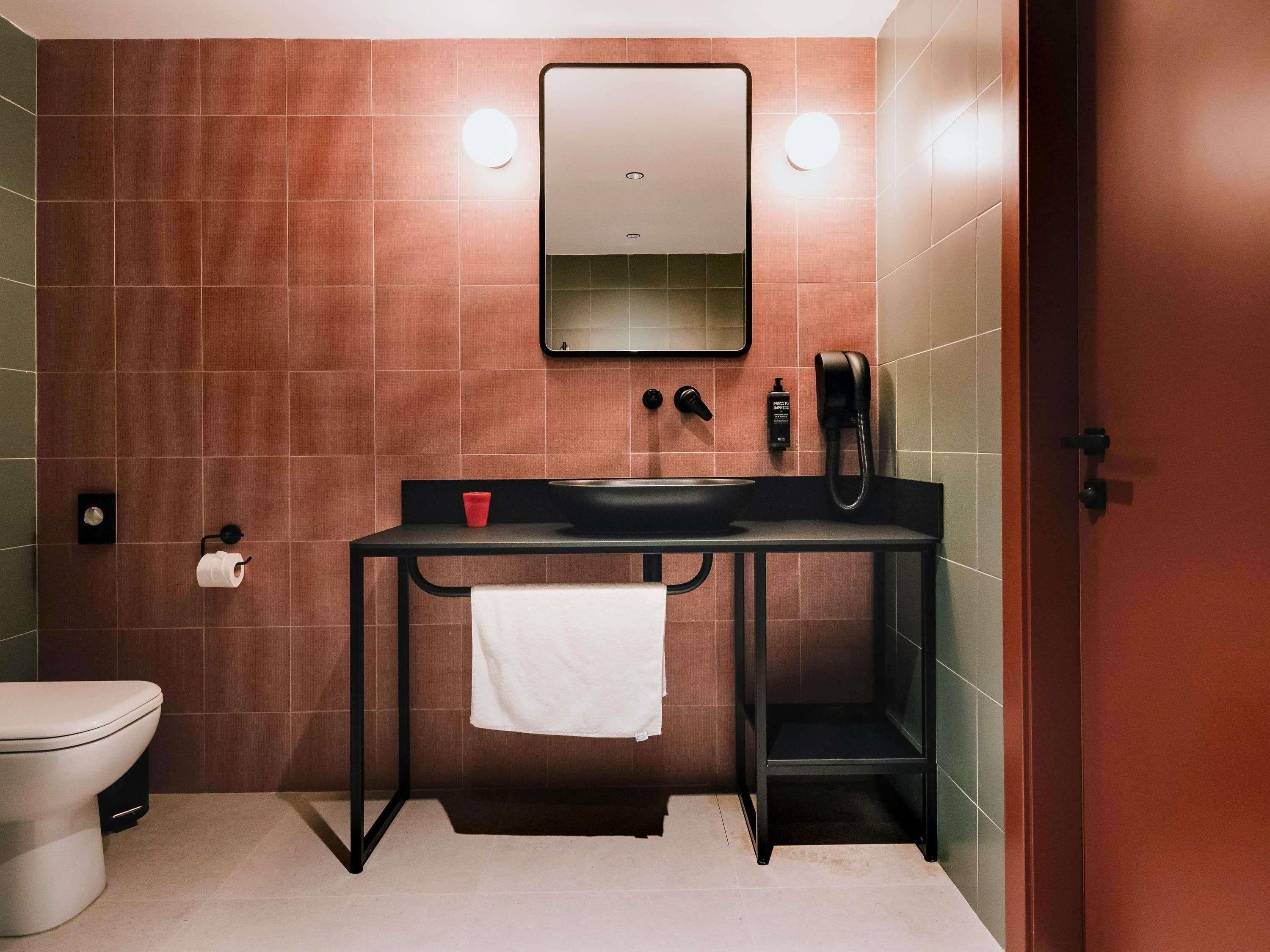 A bathroom with a toilet, sink, mirror, and towel rack.