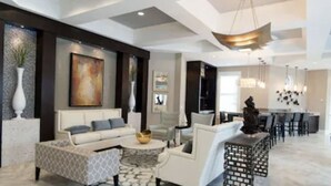 A spacious living room with a modern sofa set, a coffee table, and a dining area with a long table and chairs. - Marvel Villa - 20 minutes to Disney (Davenport)