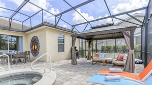 A covered outdoor area with a pool, lounge chairs, and a patio with a table and chairs. - Marvel Villa - 20 minutes to Disney (Davenport)