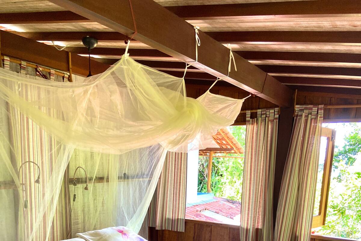 Una cama con colcha estampada, dosel y toallas.