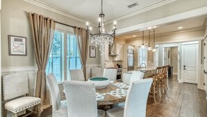 Un coin repas avec une table ronde, des chaises à revêtement blanc et un lustre.
