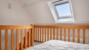 A bedroom with a sloped ceiling, a skylight, a wooden bed frame, and a white mattress. - 300m from the beach, 2 adults - 2 children (Saint-Gildas-de-Rhuys)