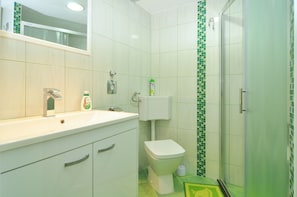 A bathroom with a white sink, a toilet, and a shower area. - Spacious Modern Apt. With big Patio and sea View (Split)