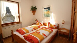 A bedroom with a bed, a window with curtains, a wall-mounted plant, a painting, and a bedside table with a lamp. - Alone in indoor pool, sauna, steam sauna, directly on the banks of the Moselle, balcony (Zell/Mosel)