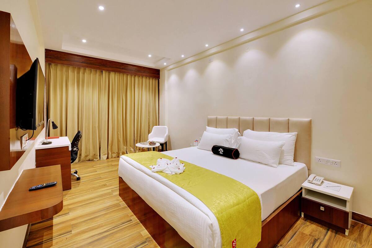 Una habitación de hotel con cama, mesita de noche, silla, escritorio y televisor.