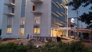 Moderni rakennus, jossa on useita kerroksia, parvekkeita ja katettu ulkoalue, jossa on istuimia.