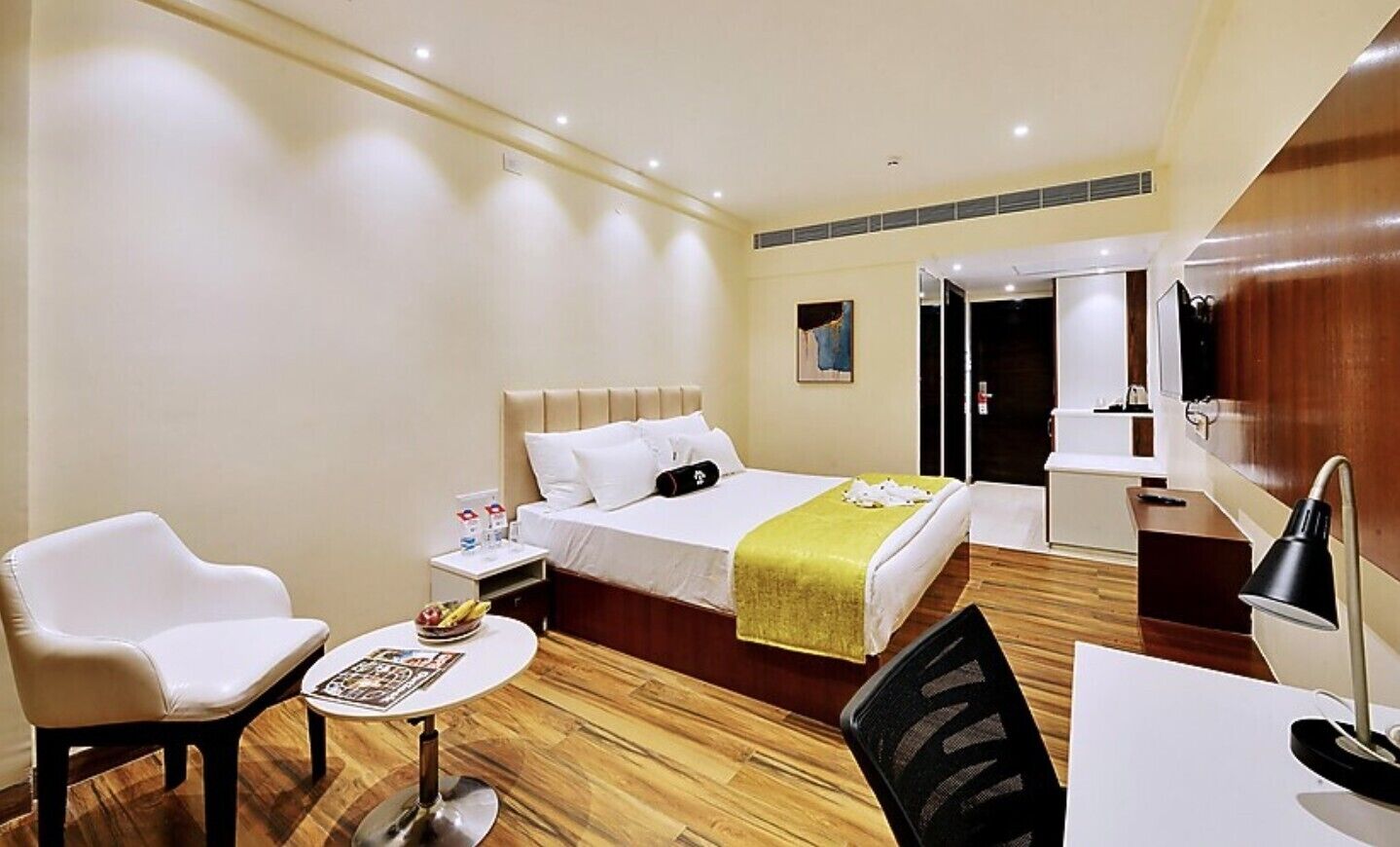 Une chambre d’hôtel comprenant un lit, un bureau, une chaise, une petite table et une table de chevet.