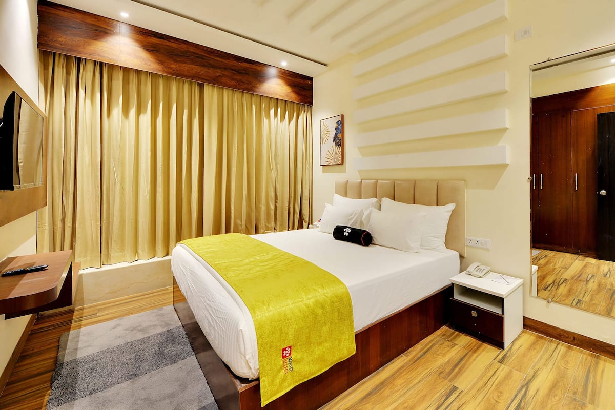 Una habitación de hotel con una cama, una mesita de noche y un espejo.