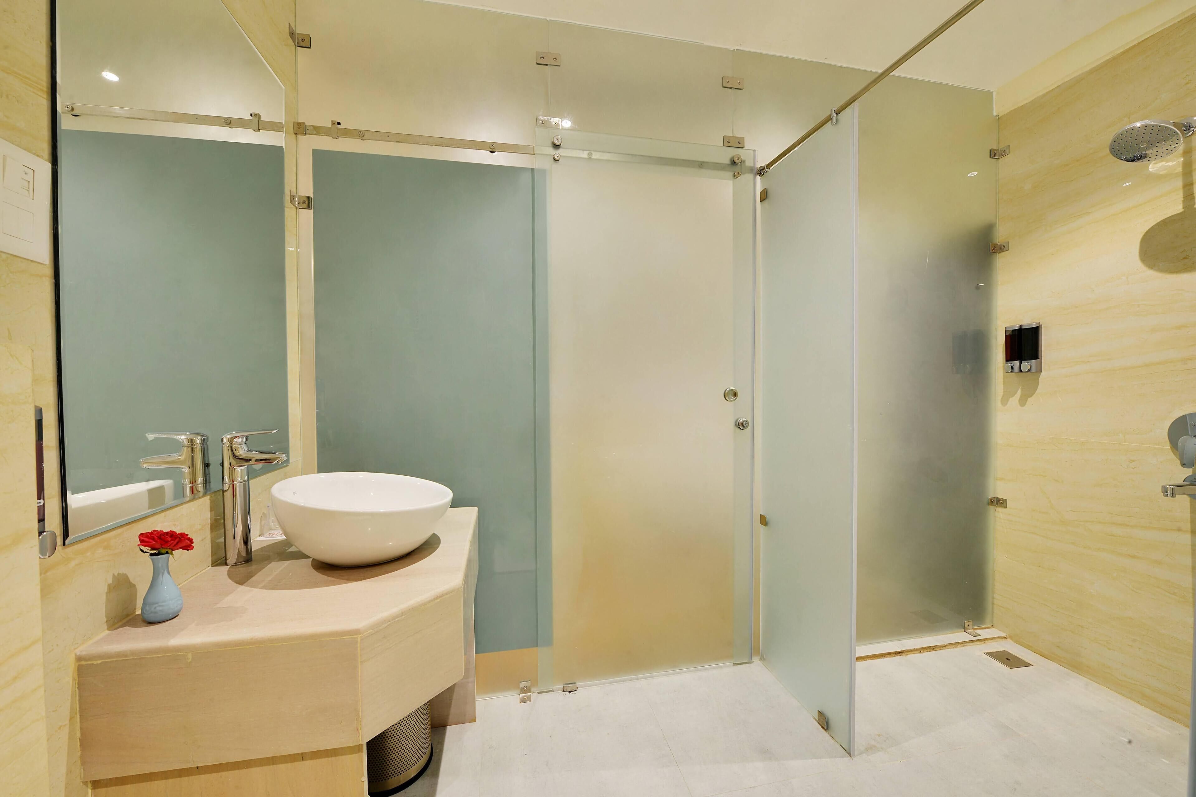 A modern bathroom with a glass-enclosed shower, a white sink, and a mirror above it.