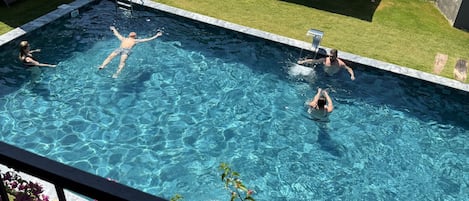 Una piscina con agua azul cristalina, rodeada de sillas de descanso y sombrillas.