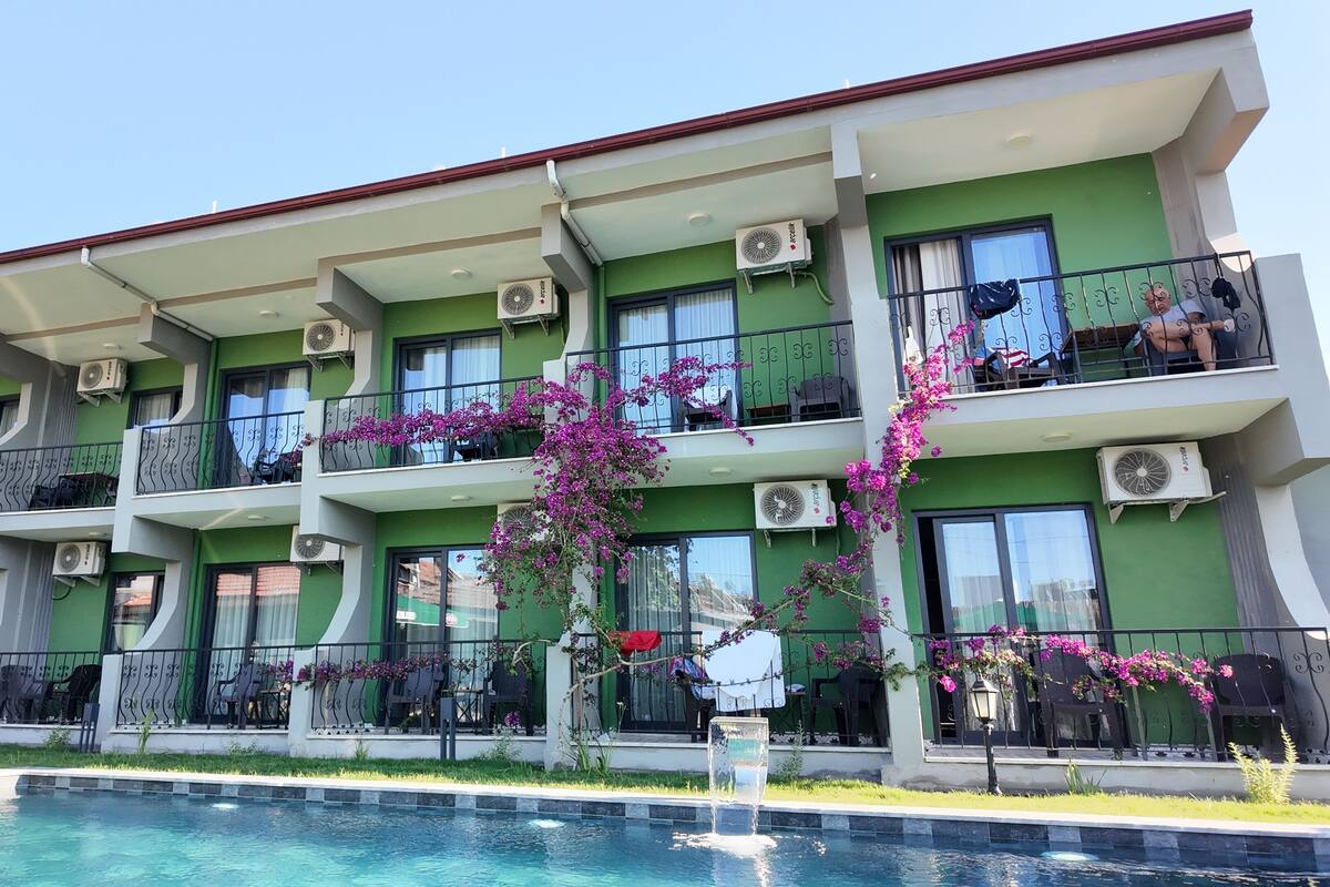 A multi-story hotel with balconies, air conditioning units, and a swimming pool.