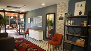 Un interior moderno con piso estampado, un tapete rojo y negro, un armario blanco, una estantería de madera y un espejo.