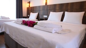 Habitación de hotel con dos camas, ropa de cama blanca y una decoración de toallas y flores.