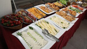 Un bufé con diversas opciones de comida, como frutas, quesos y ensaladas.
