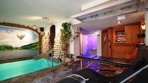 Ein Wellnessbereich mit Whirlpool, Massagetischen und einer Steinwand mit Wandgemälde.