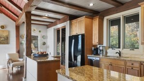 A kitchen with wooden cabinets, granite countertops, a black refrigerator, and a window with a view of trees. - Looks Like Love! on Valentine Lane: 2 Levels of Luxury Home w Mtn Views, Porches (Highlands)
