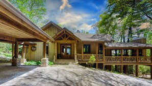 A wooden cabin with a covered porch, a stone entrance, and a deck with a railing. - Looks Like Love! on Valentine Lane: 2 Levels of Luxury Home w Mtn Views, Porches (Highlands)