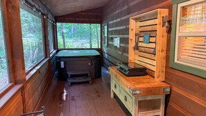 Ein Holzblock-Interieur mit einer Whirlwanne, einer Holzschrank und einem Fenster mit Blick auf einen Wald.