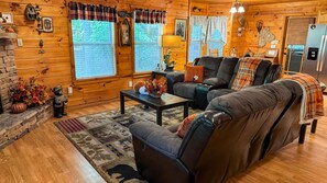 A cozy cabin interior with a sectional sofa, a coffee table, and a fireplace.