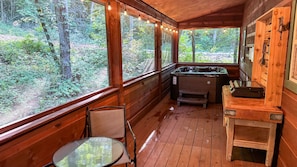 A wooden cabin with a hot tub, a table, and chairs.